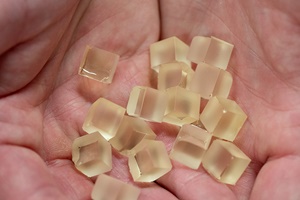 A hands holds cubes of the PECAN resin. An NREL scientist holds small cubes of the PECAN resin. Photo by Werner Slocum NREL